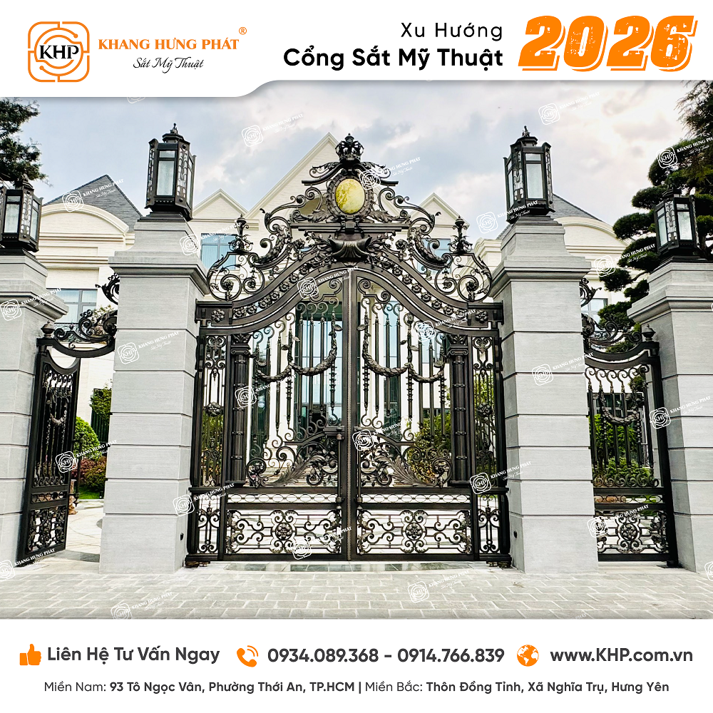 xu hướng cổng sắt mỹ thuật phong cách cổ điển Pháp (Mã số: KHP-2026-01) sở hữu hoa văn uốn lượn dày đặc, đối xứng hoàn hảo qua tâm đá phong thủy hình elip mạ vàng giả cổ, kết hợp hệ cột đá bệ vệ.